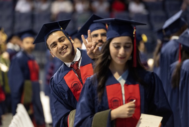 Graduate smiling while throwing the peace sign.