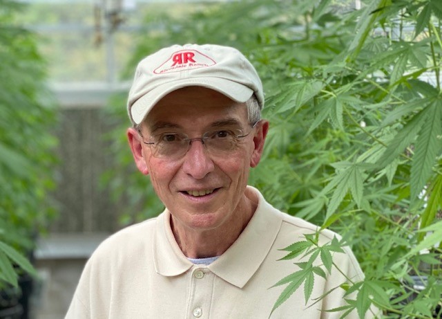 Don Stanford standing with a marijuana plant.