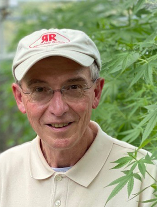 Don Stanford standing with a marijuana plant.