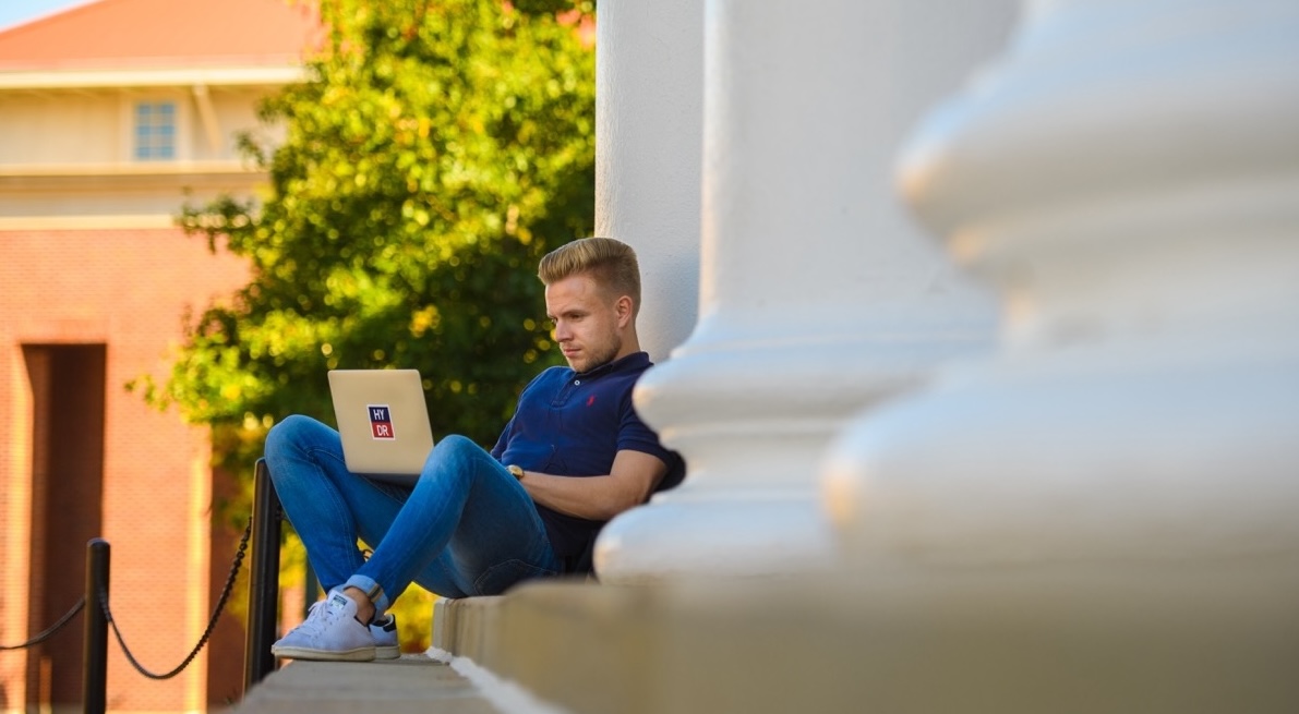Student on his computer sitting on the Lyceum steps.