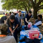 Student pharmacists assist adults with health fair screening at outdoor park