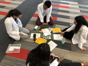 Four students sit in a circle on the floor talking