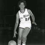 Black and white photo of Kimsey O'Neal Bailey dribbles a basketball in her uniform