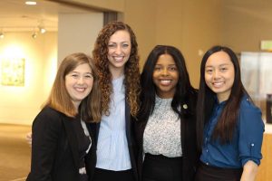 Four female students in business attire stand together for group photo