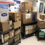 Cardboard boxes filled with PPE donations stacked on carts