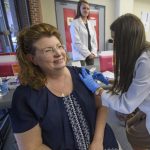 Loree Allen receives her flu shot from a female pharmacy student.
