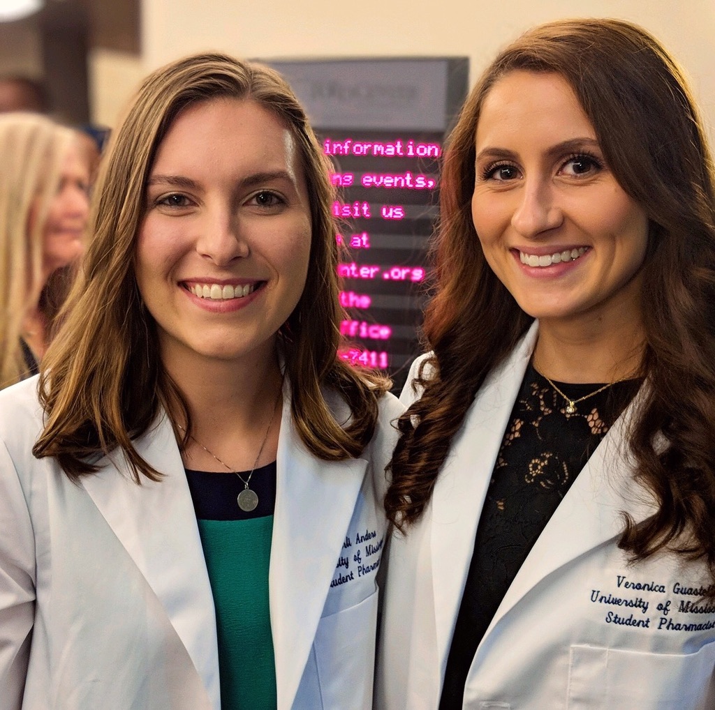 Veronica and a female student pose together in their white coats.