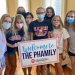 Group of students in masks holding a sign that says 'Welcome to the Phamily'
