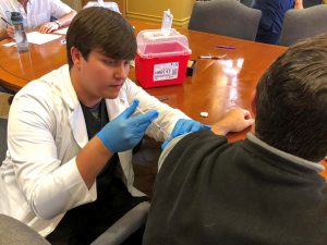 A male student gives a patient his flu shot.
