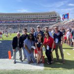Group of students and faculty standing on the field at Vaught-Hemingway Stadium