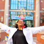 Licamied Macklin throws colorful confetti in the air while wearing her white coat