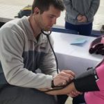 A male pharmacy student takes blood pressure of a patient
