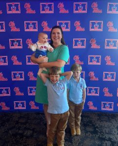 Mollie Spencer with her three kids in front of an Ole Miss Alumni Association backdrop