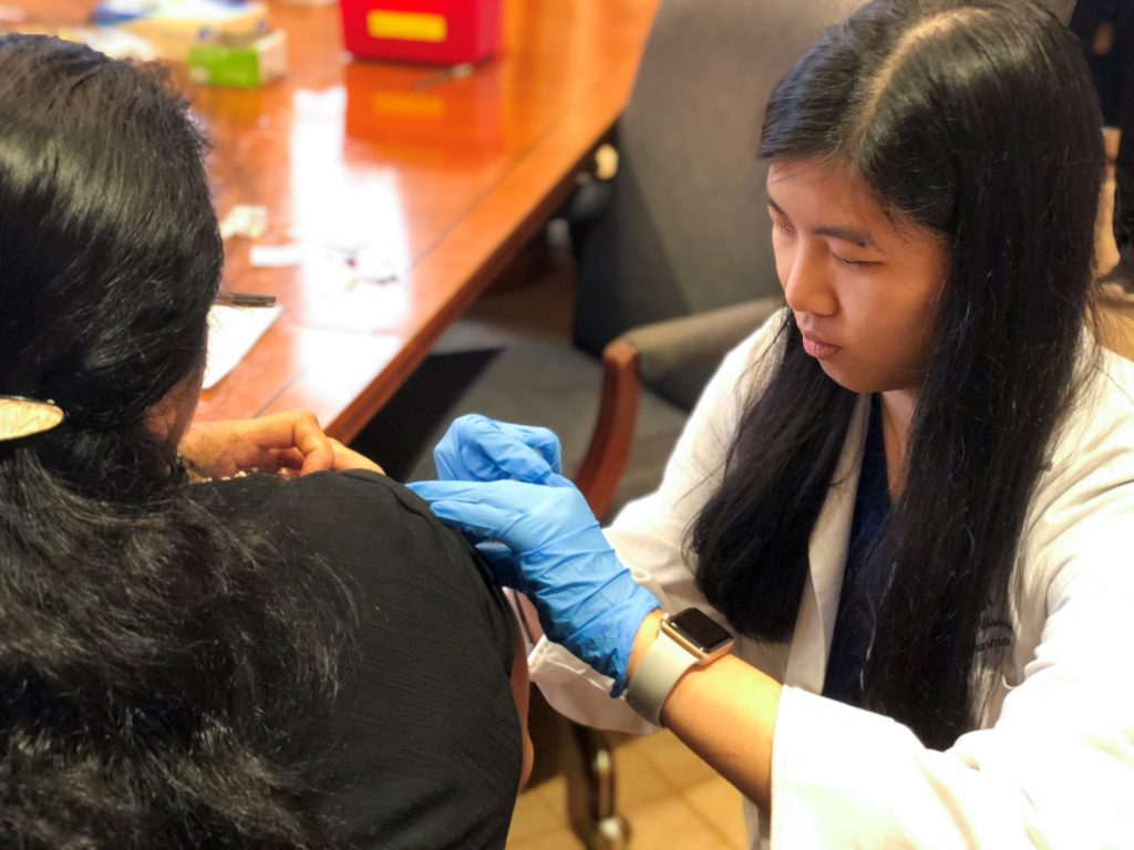 A female student gives a patient the flu shot